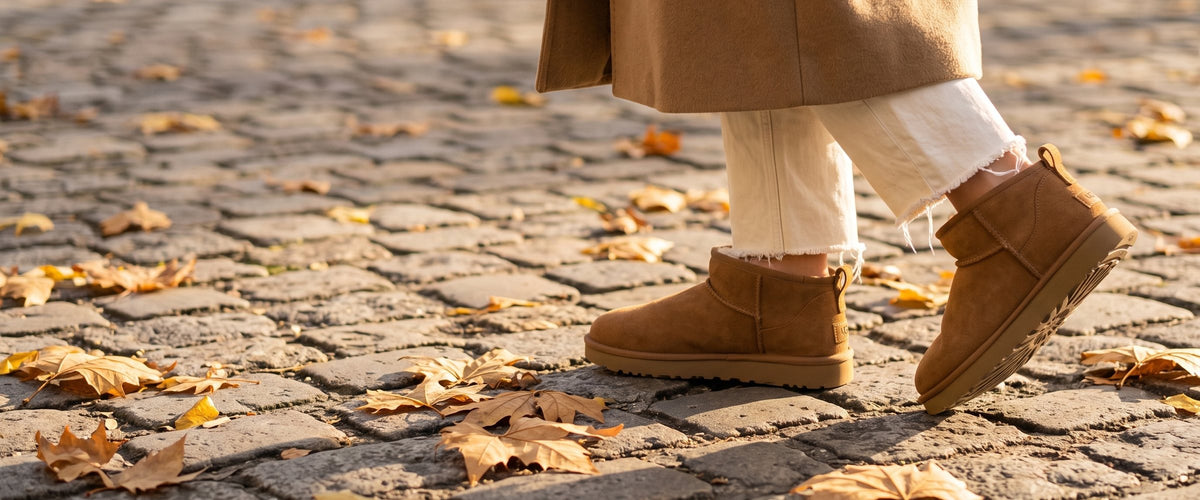 Pár UGG Classic Ultra Mini Chestnut na pařížské dlažbě pokryté podzimním listím (obrázek vytvořený pomocí AI)